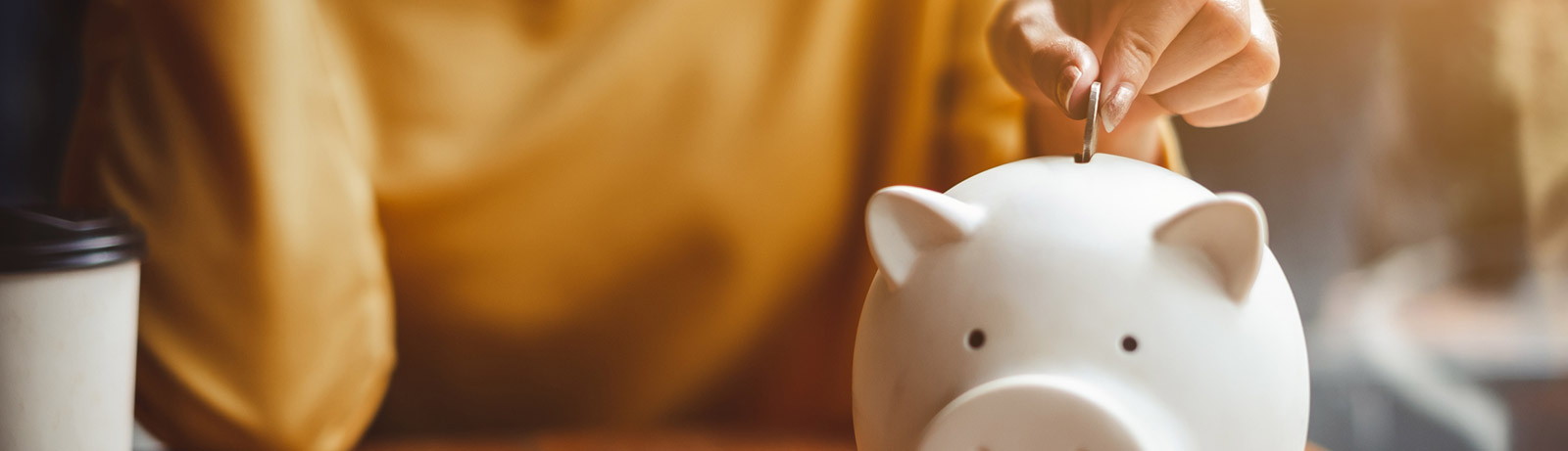 Close up of woman putting coins in piggy bank