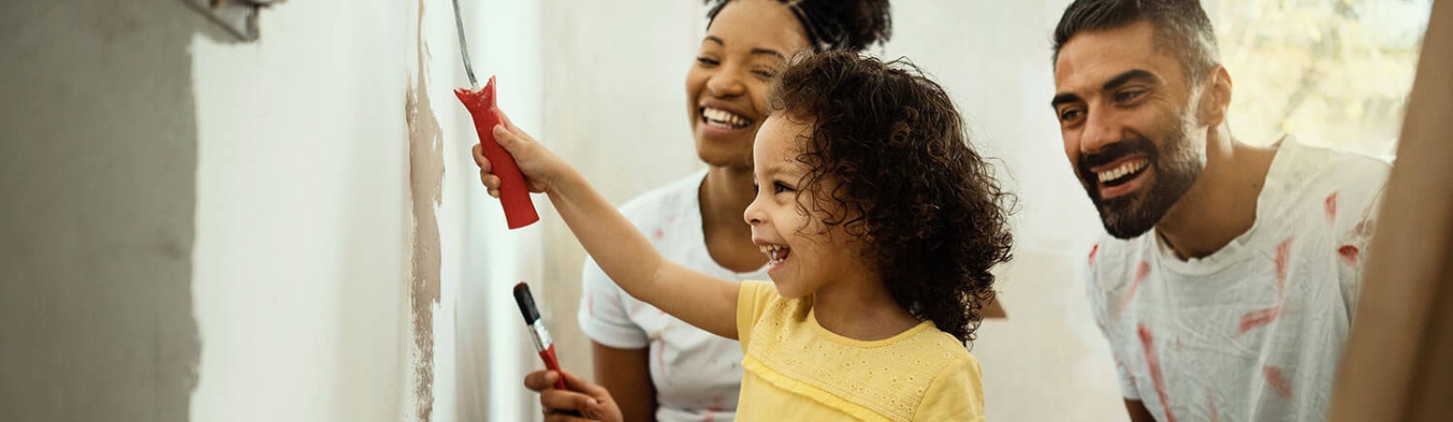 a family painting a wall in their house